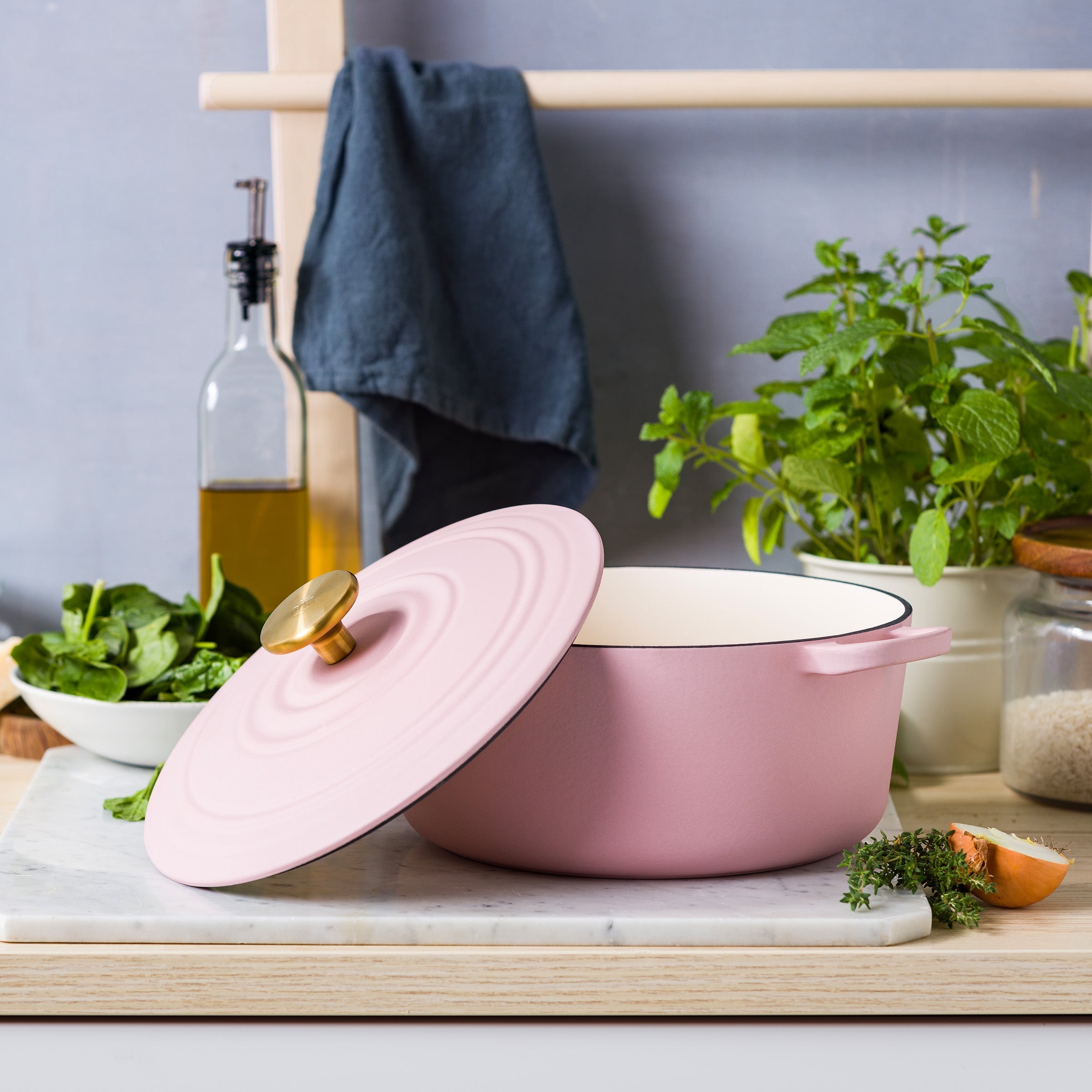 Roze BK Bourgogne braadpan met schuin geplaatste deksel op marmer, spinazie en tijm ernaast