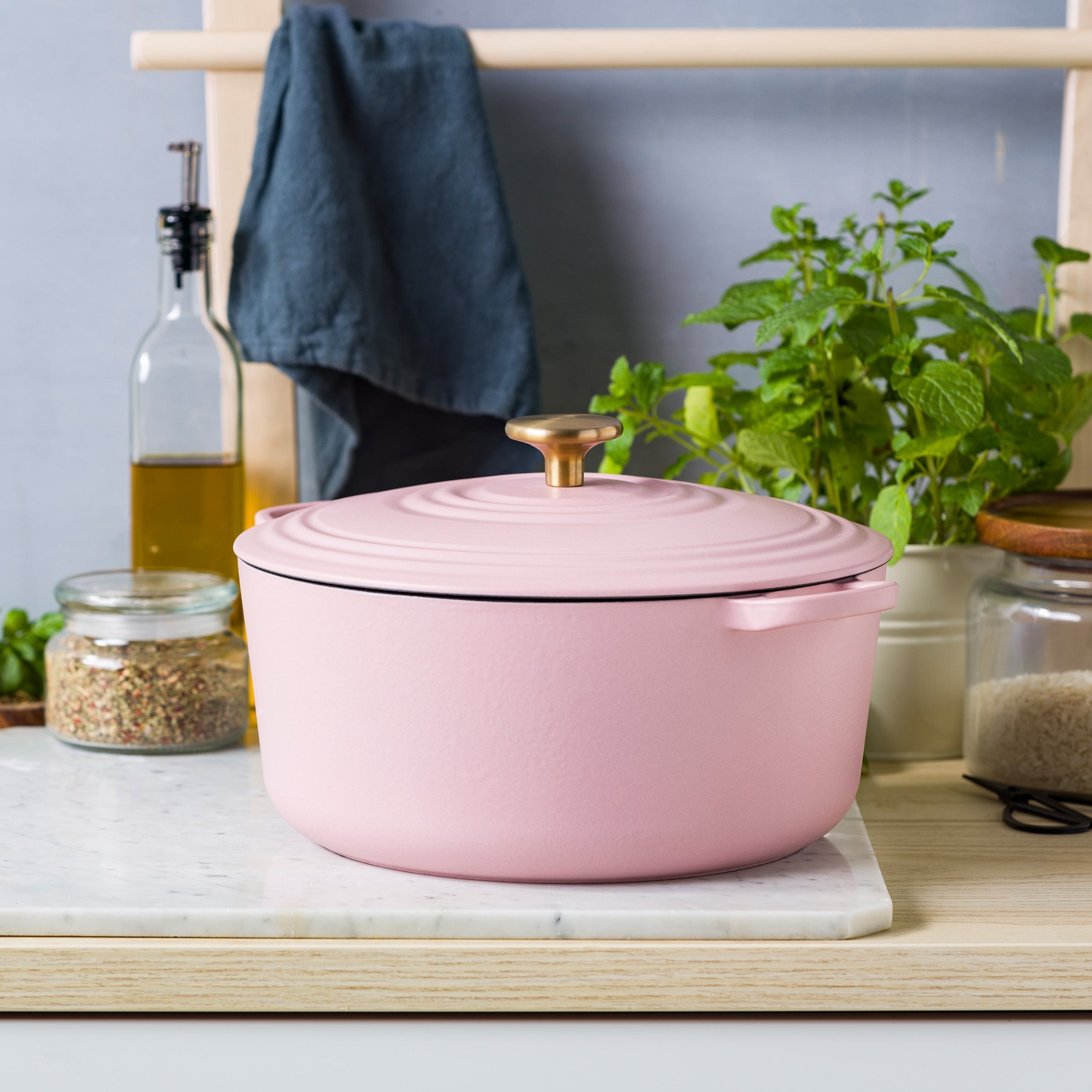 Roze BK Bourgogne braadpan met goudkleurige knop op marmer, olie en verse munt ernaast