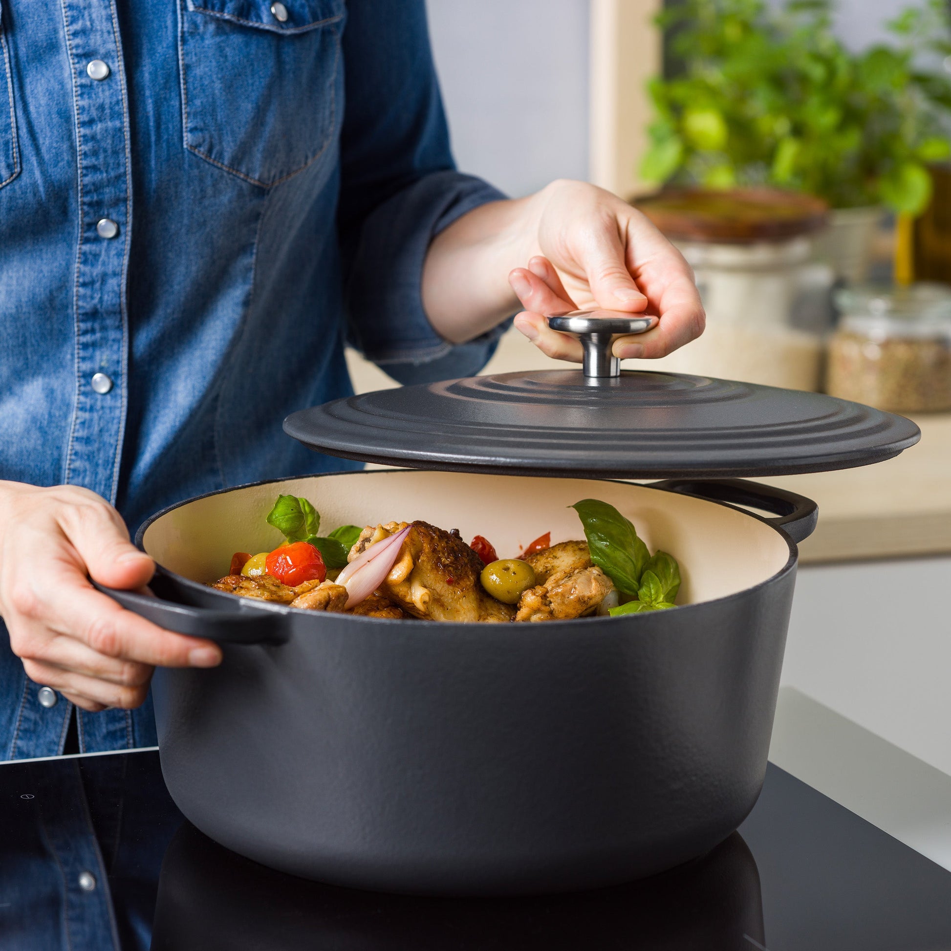 Hand tilt de deksel van de BK Bourgogne braadpan Earl Grey op inductie, gevuld met vlees en basilicum.