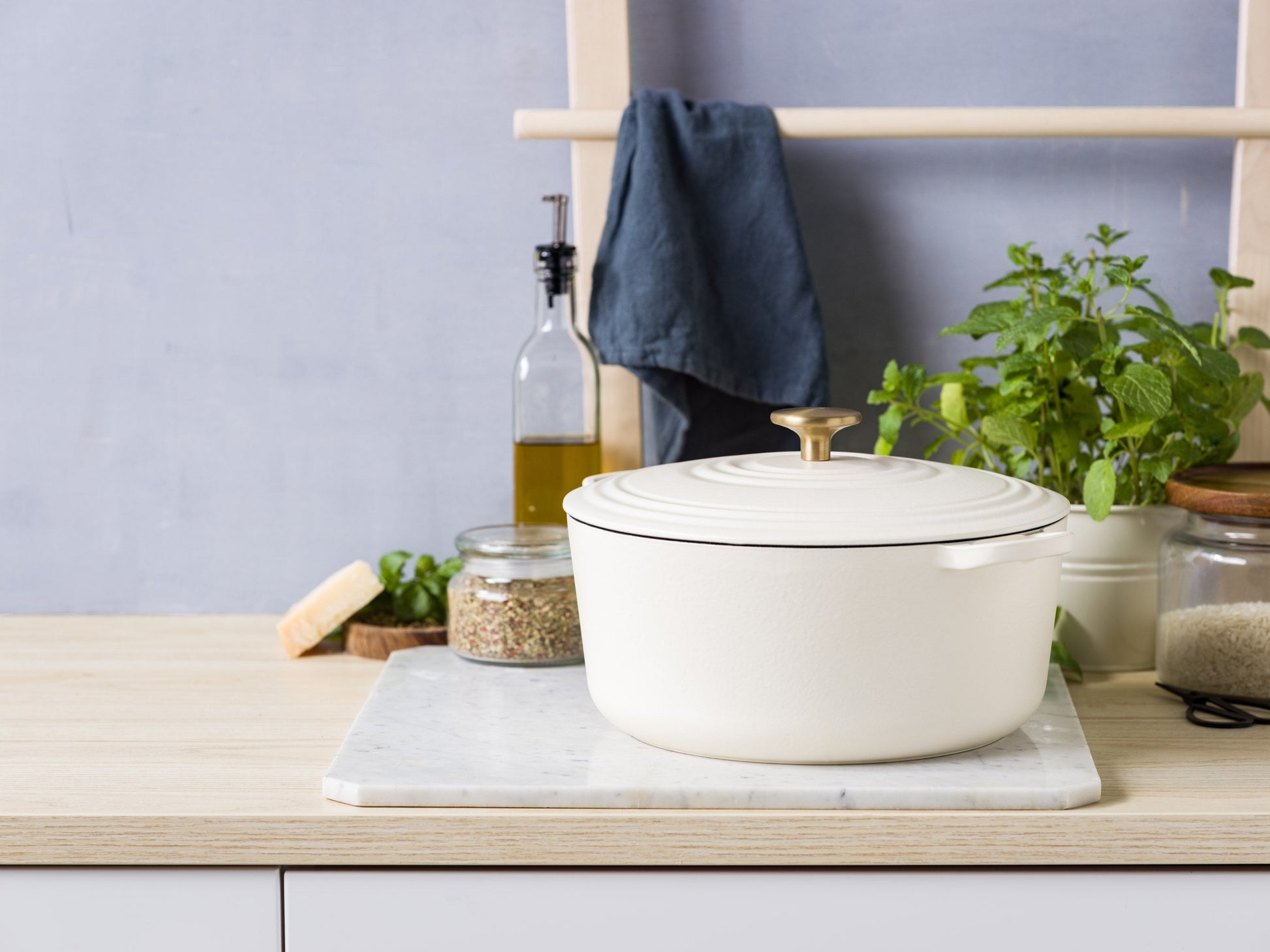 BK Bourgogne braadpan in Cream White met goudkleurige knop op marmer, olie en kruiden ernaast