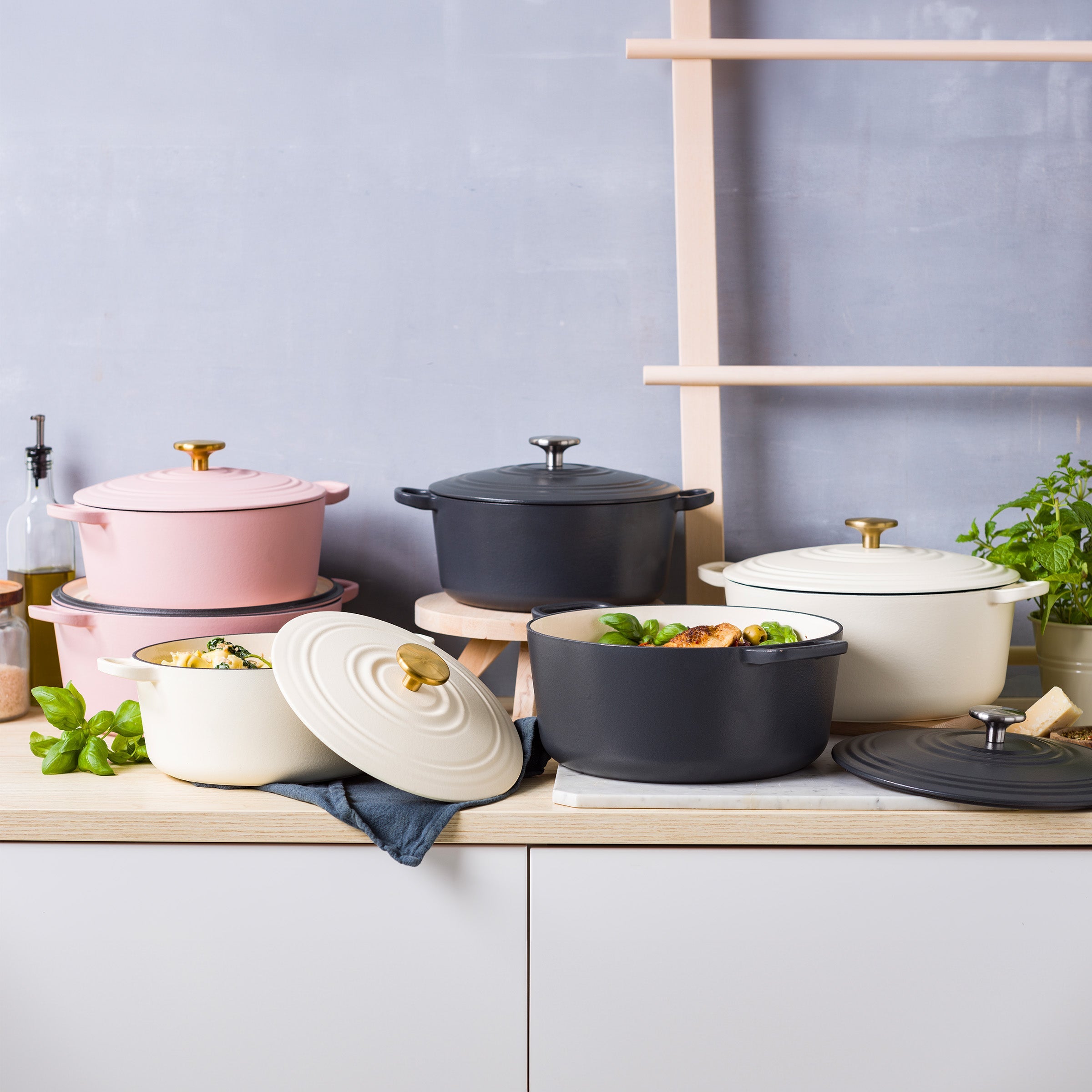 Collectie BK Bourgogne braadpannen in roze, zwart en crèmewit op een aanrecht met munt