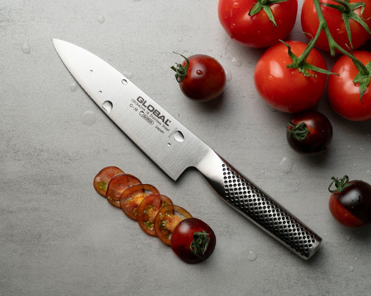 Global G-58 koksmes naast tomaten en fijn gesneden tomaatplakjes op een grijs werkblad