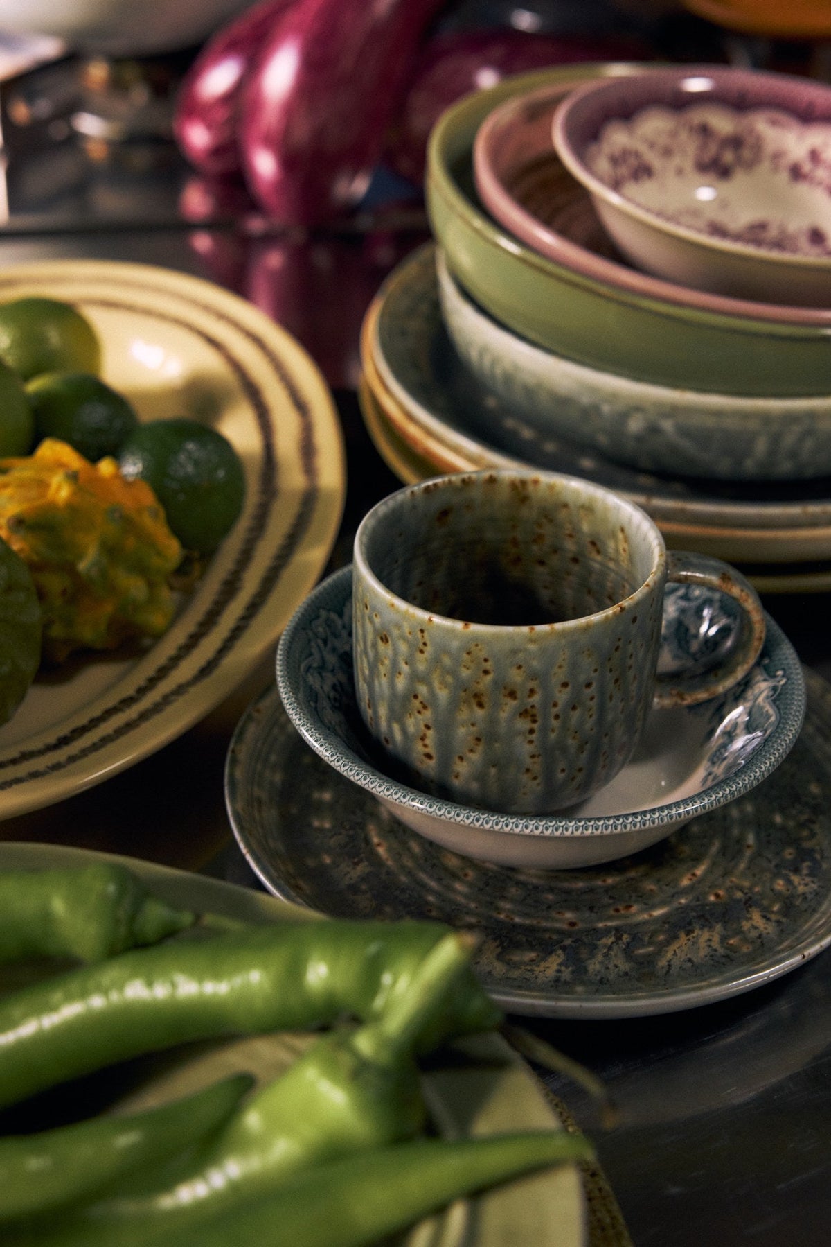 HKLiving Chef Ceramics mok Rustic Green met gespikkeld groen glazuur, op een schotel tussen ander servies