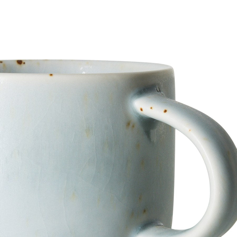 Close-up van het lichtblauwe glazuur met bruine spikkels en het oor van de Chef Ceramics mok Soft Blue