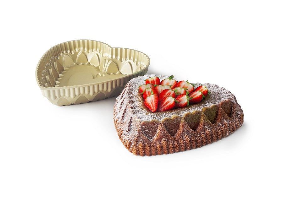 Ibili Hartvormige Bakvorm, bakvorm naast een gebakken hartvormige cake met aardbeien en poedersuiker