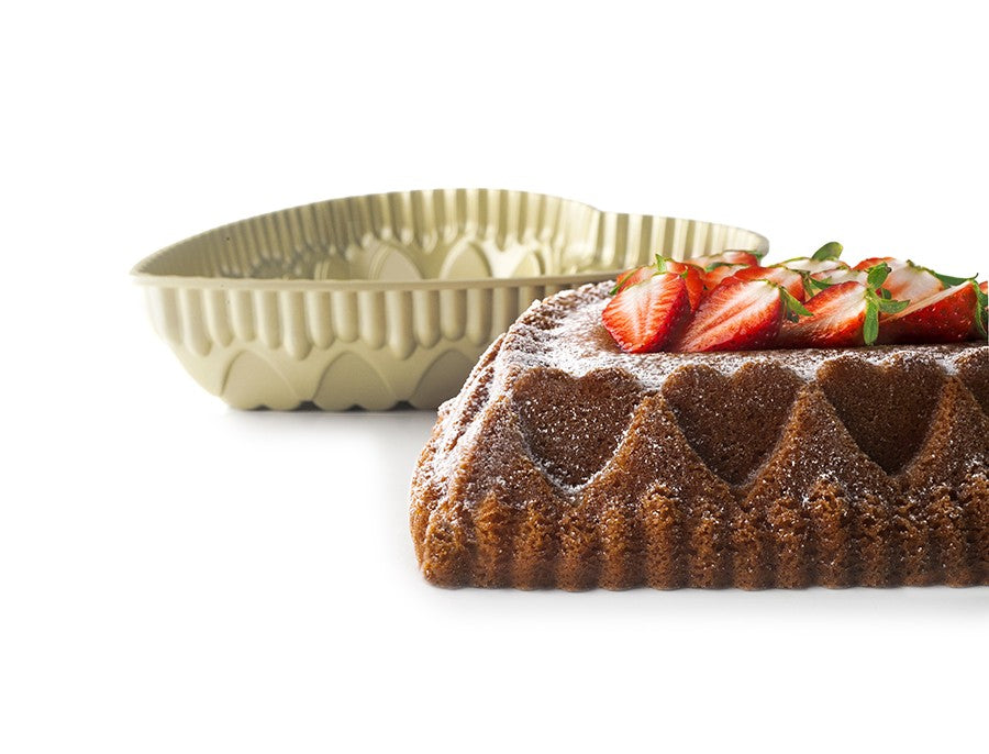 Ibili Hartvormige Bakvorm, close-up van de bakvorm met gebakken hartvormige cake, aardbeien en poedersuiker groot in beeld