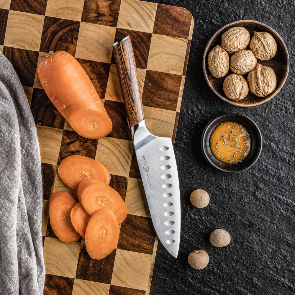 Kazoku Nisei santoku naast schijfjes wortel en nootmuskaat op een snijplank met ruitpatroon