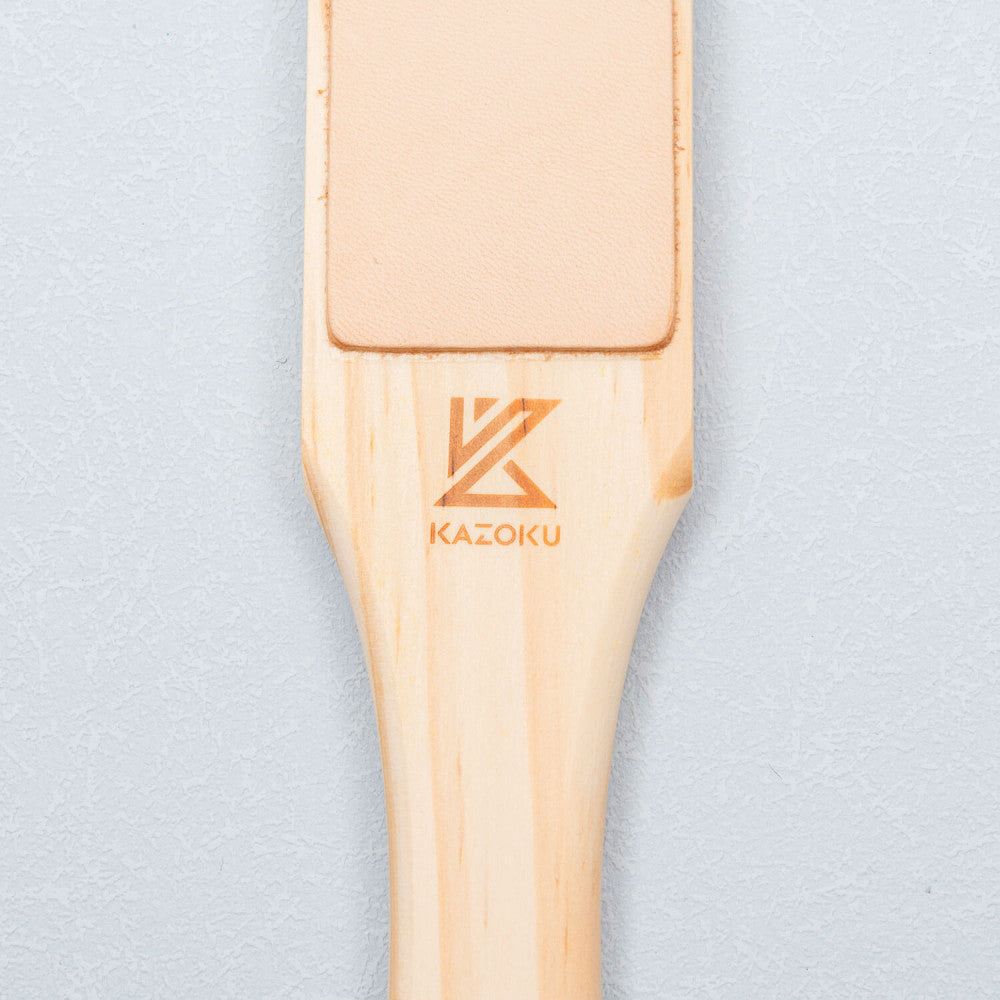 Close-up van de houten handgreep met Kazoku-logo en de gladde leren zijde van de paddle strop