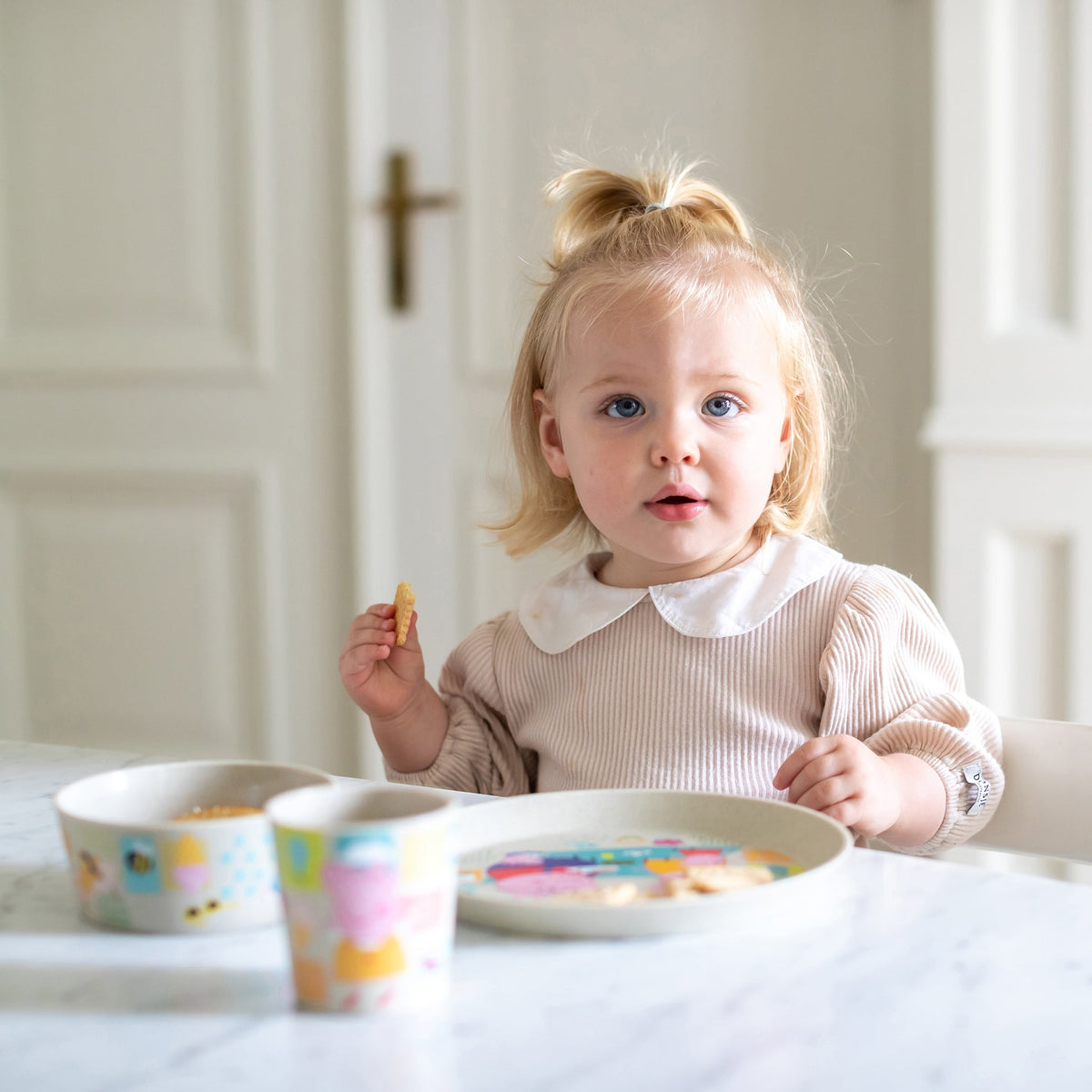 Peuter aan tafel met het Peppa Pig-bord, schaaltje en beker