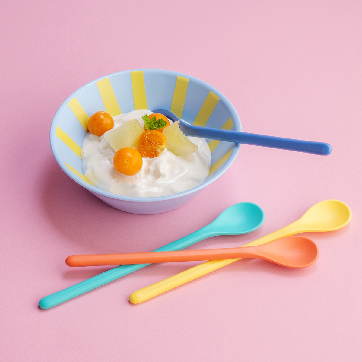 Een lange lepel in een kom yoghurt, de andere drie ernaast