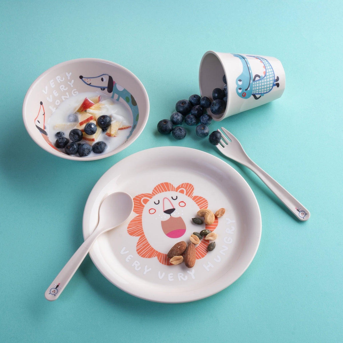 Het kinderservies met yoghurt en blauwe bessen op een blauwe ondergrond