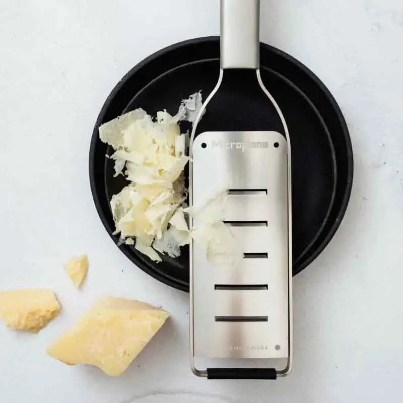 De schaaf op een zwart bord met brede vlokken Parmezaanse kaas