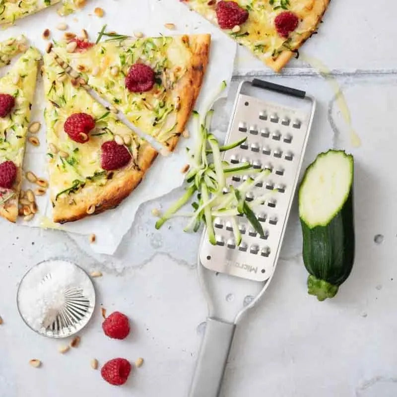 De rasp met geraspte courgette naast een plaattaart met frambozen