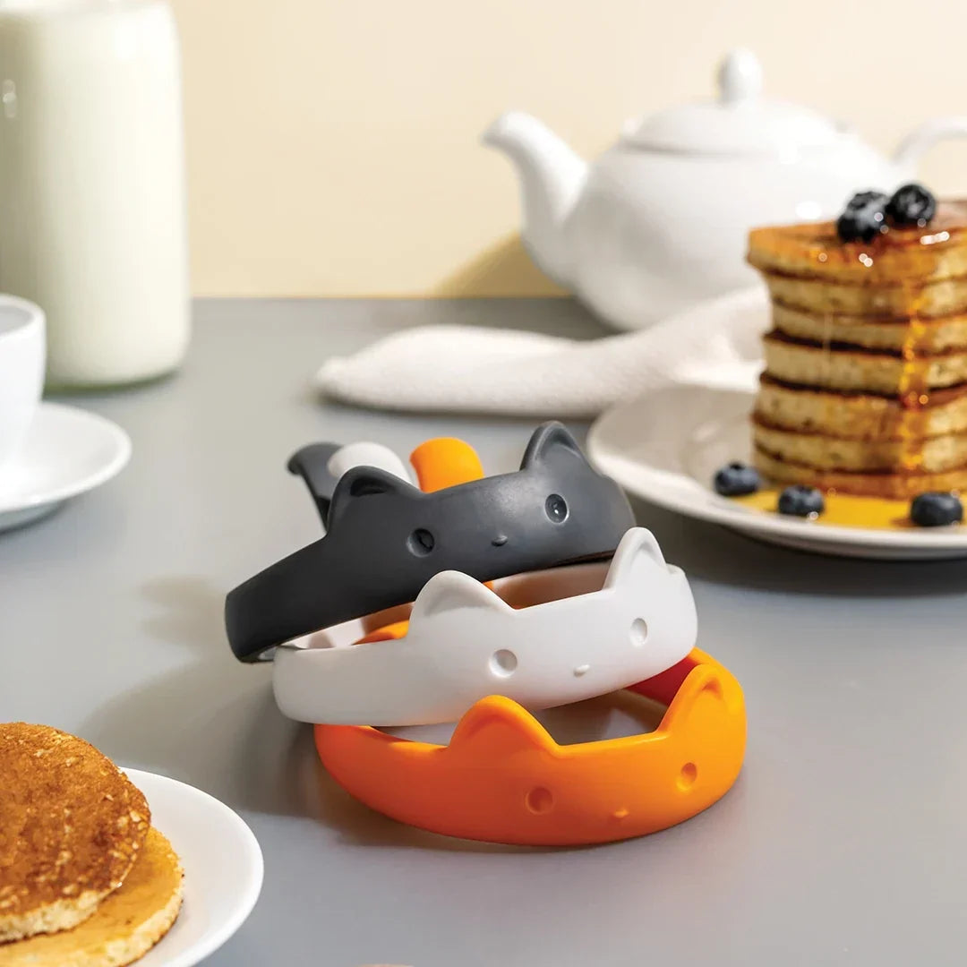 Drie kattenbakringen liggen op een aanrecht naast pannenkoeken