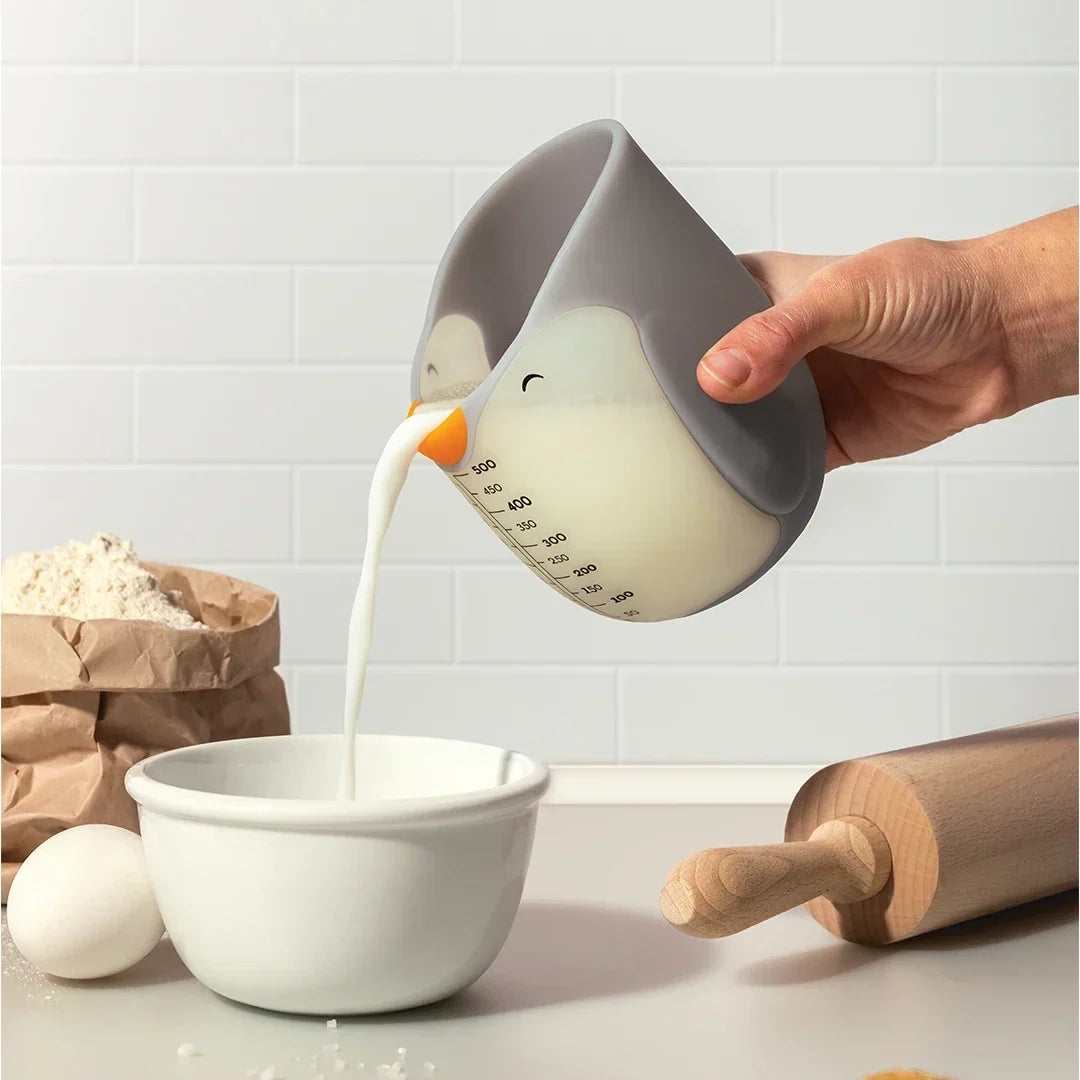 Melk wordt uit de pinguïn-maatbeker in een kom geschonken