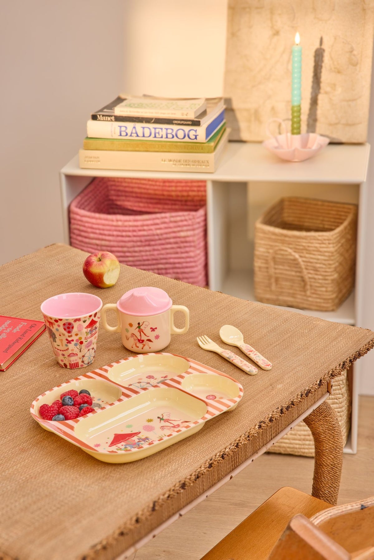 Roze vakjesbord met fruit, twee bekers en bestek op een houten tafel