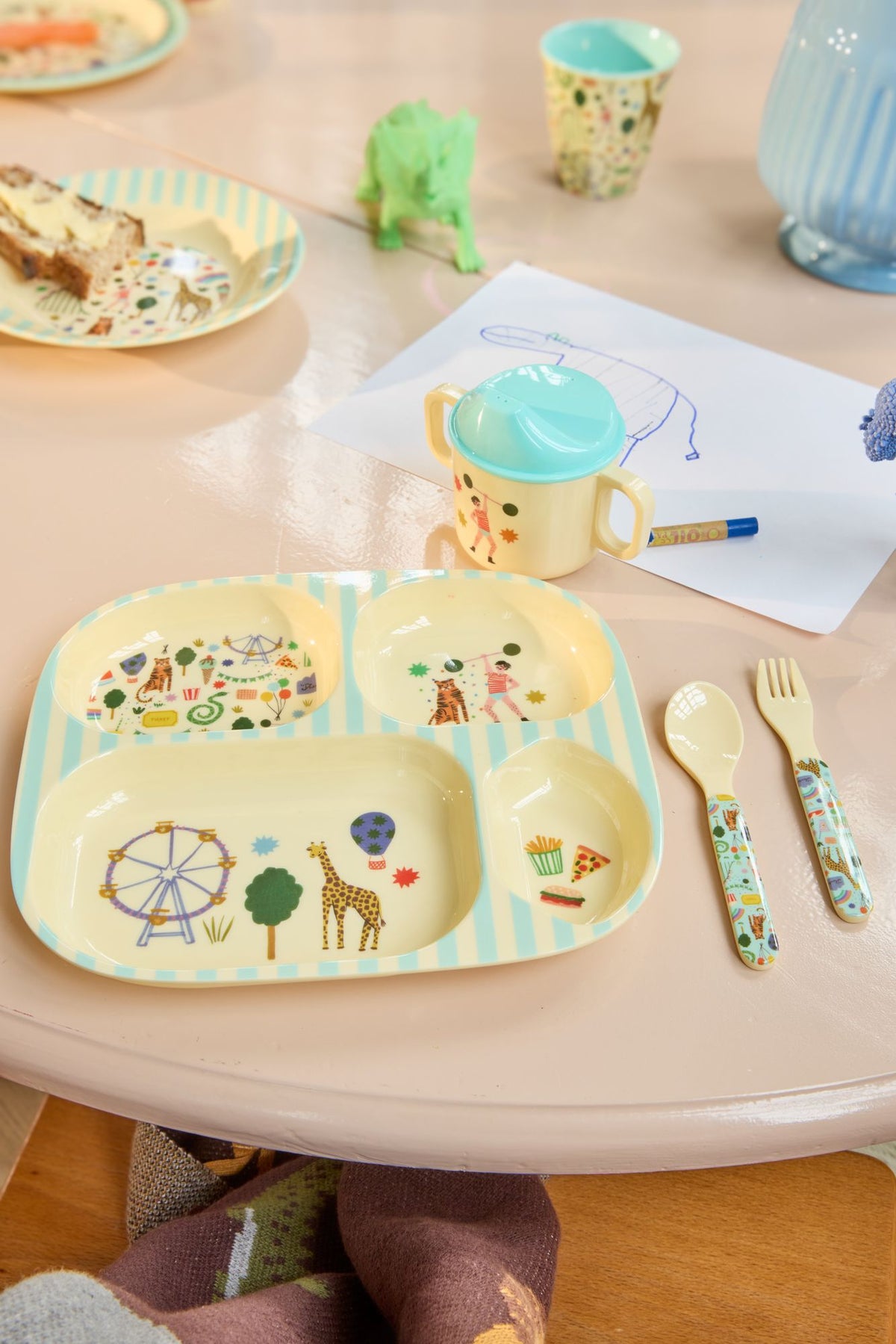 Vakjesbord met kermisprint, tuitbeker en bestek op een ronde kindertafel