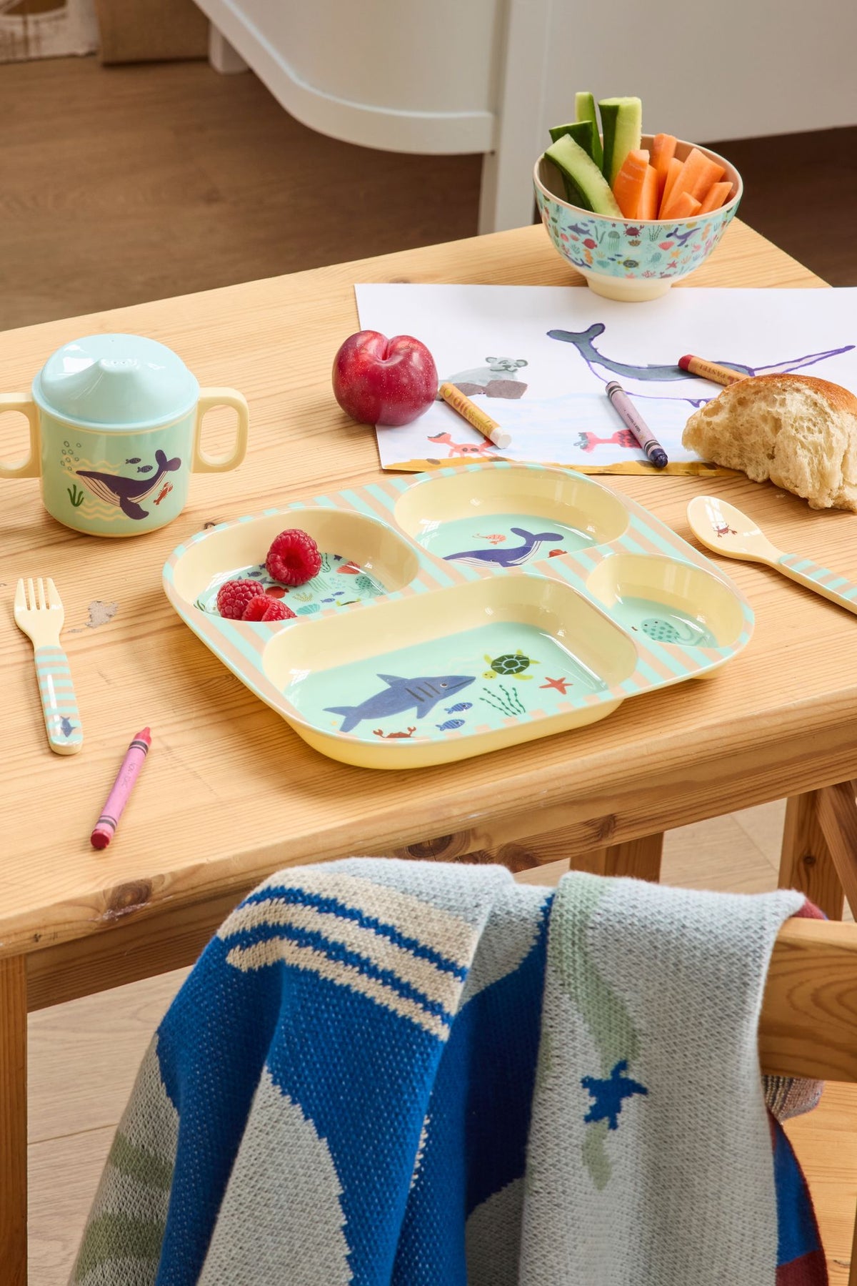 Vakjesbord en tuitbeker met zeedierenprint op een houten kindertafel met tekening
