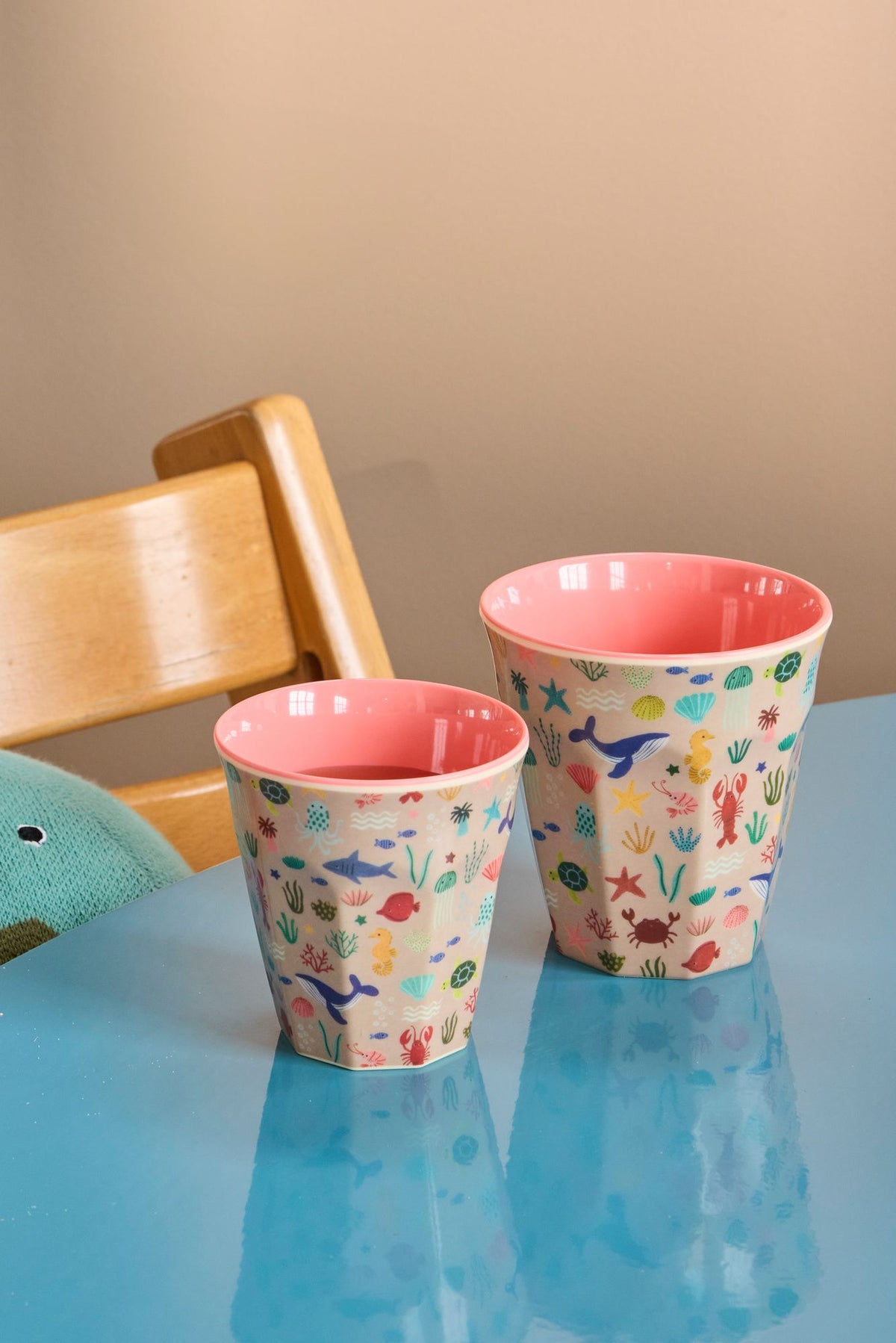Twee kinderbekers met zeedierenprint naast elkaar op een blauw kindertafeltje