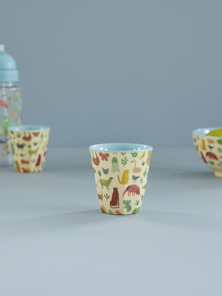 Kinderbeker met jungledieren tussen ander melamine servies op een lichte ondergrond