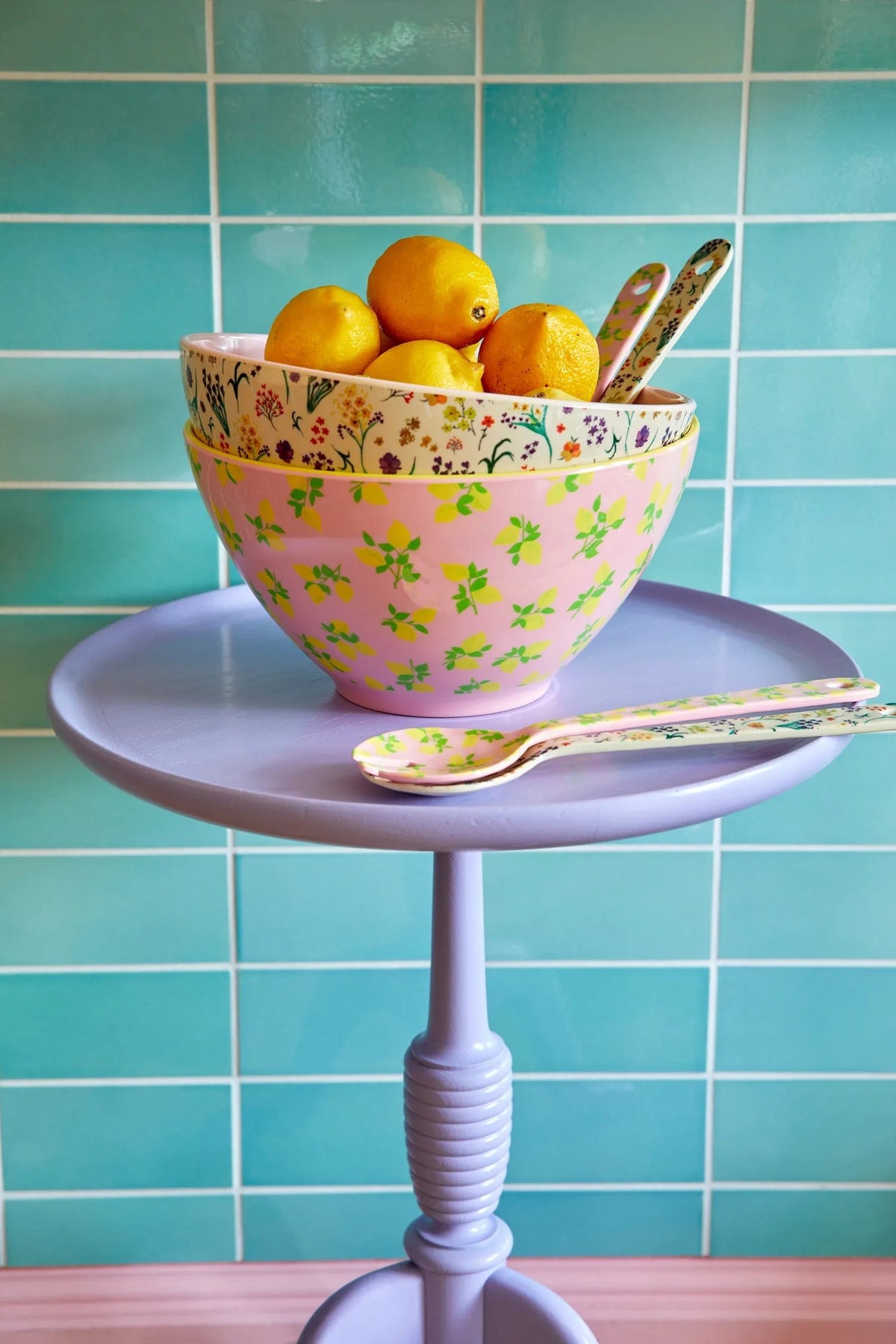 Saladeschaal met citroenen en het bijpassende saladebestek op een lila tafeltje