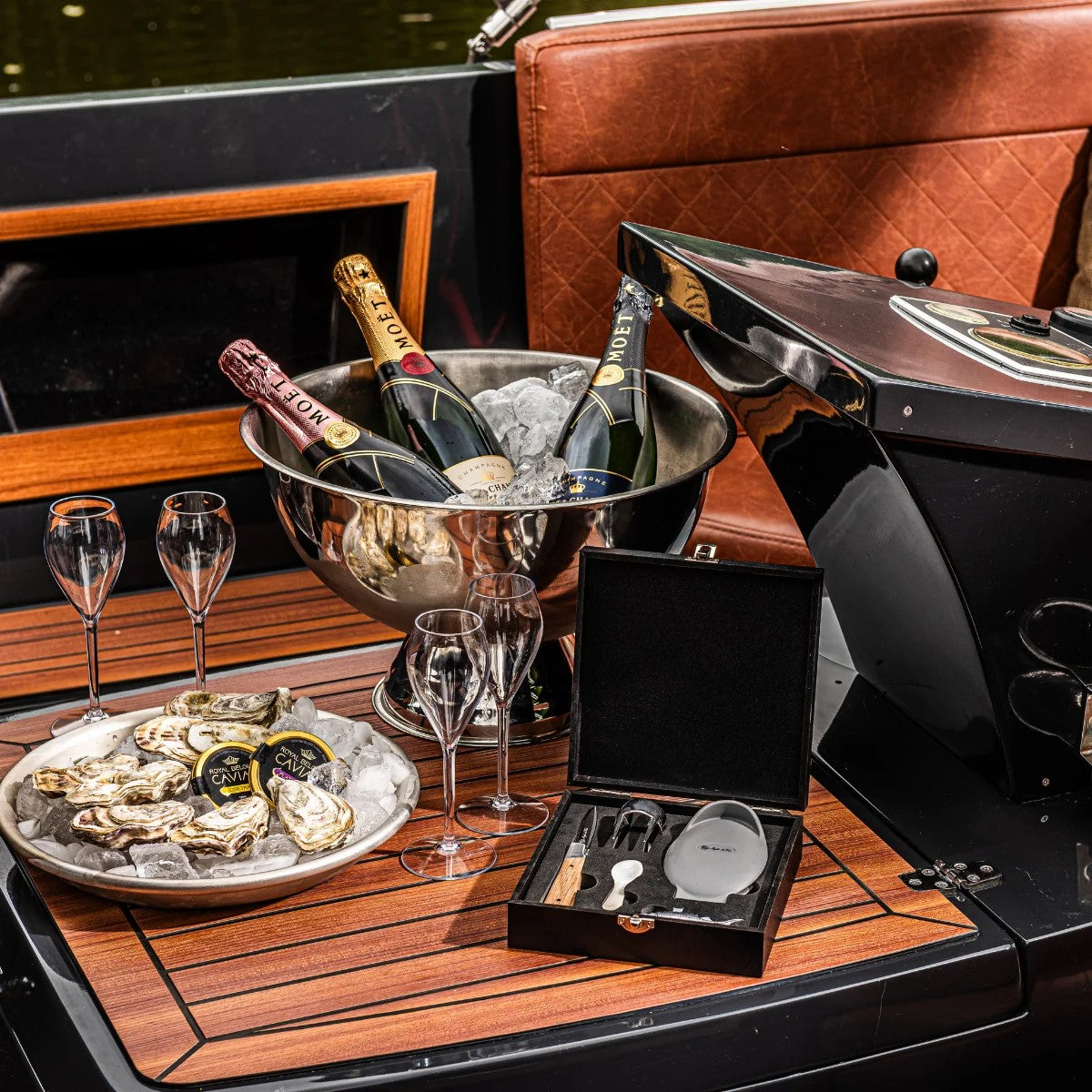 De geopende set op een houten bootdek naast een schaal met oesters en champagne
