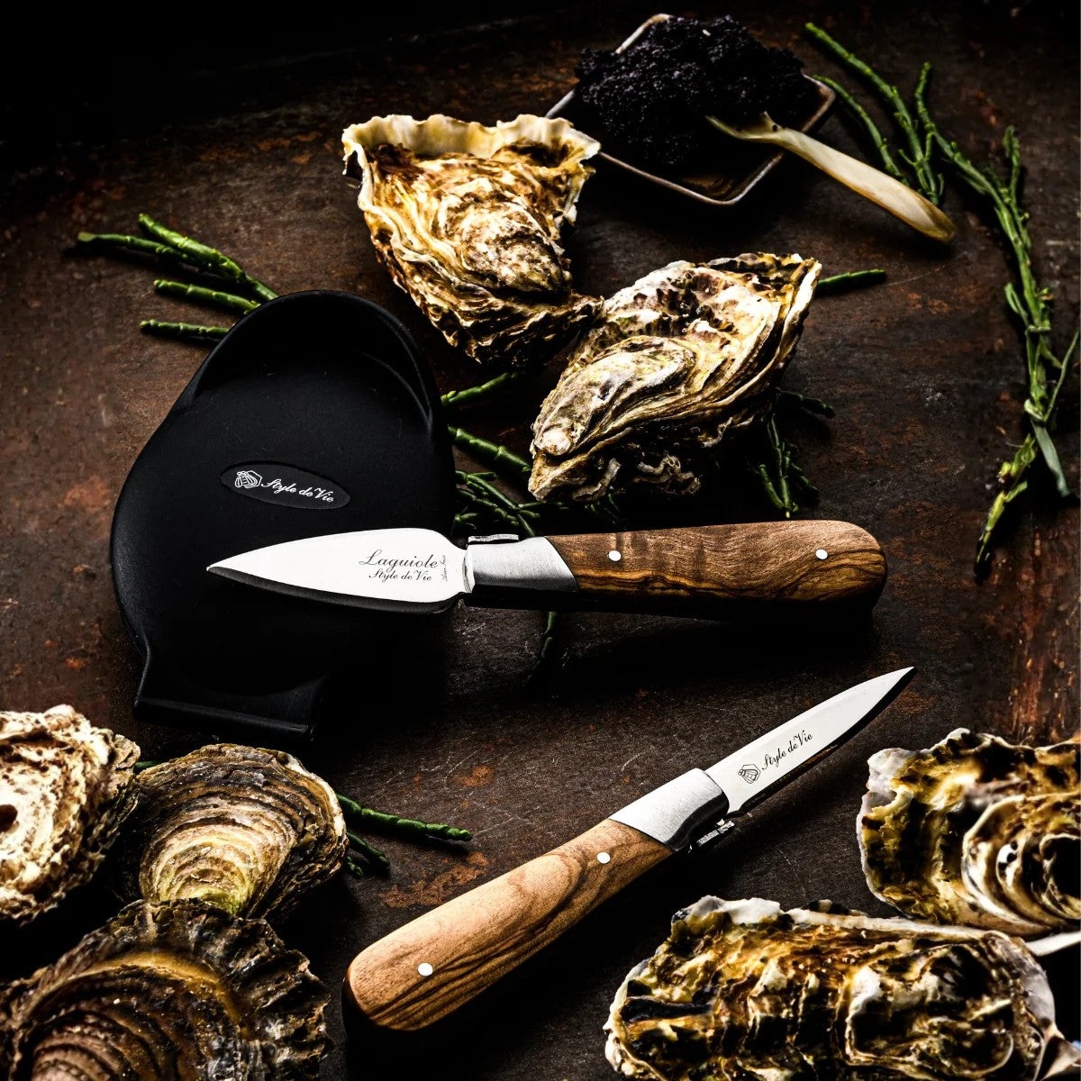 De oestermessen en de siliconen houder tussen oesters op een donkere ondergrond
