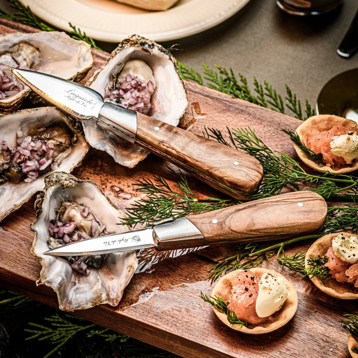 Een oestermes met olijfhouten heft op oesters op een houten plank