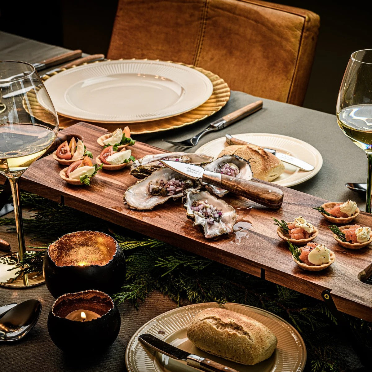 Gedekte tafel met oesters, een wijnglas en borden met hapjes