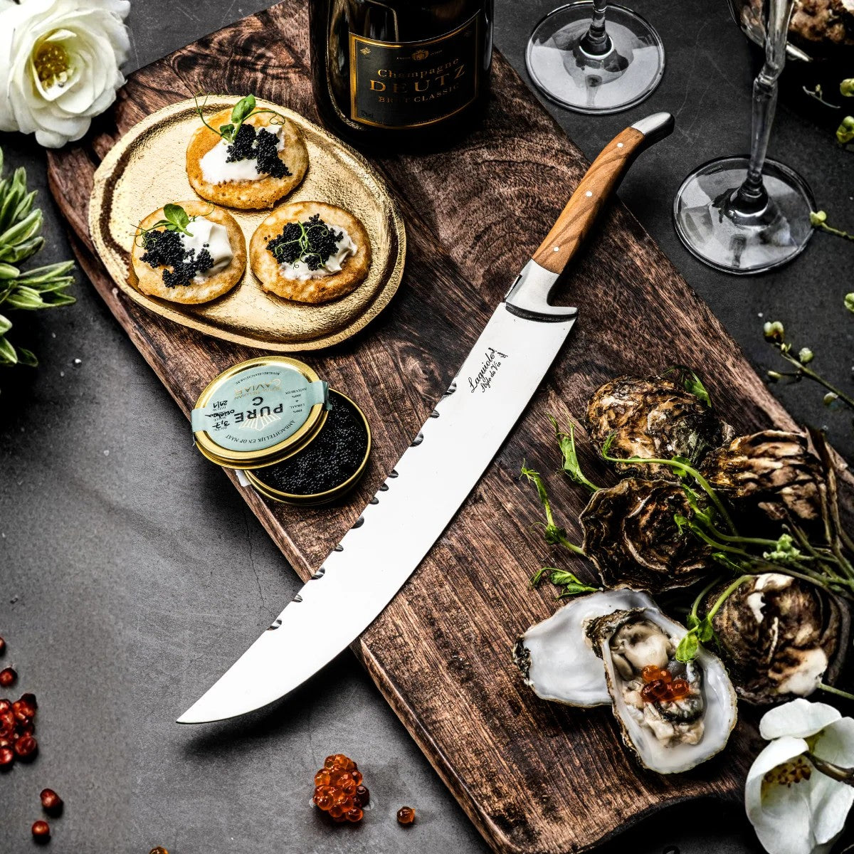 De sabel op een houten plank naast blinis met kaviaar en een fles champagne