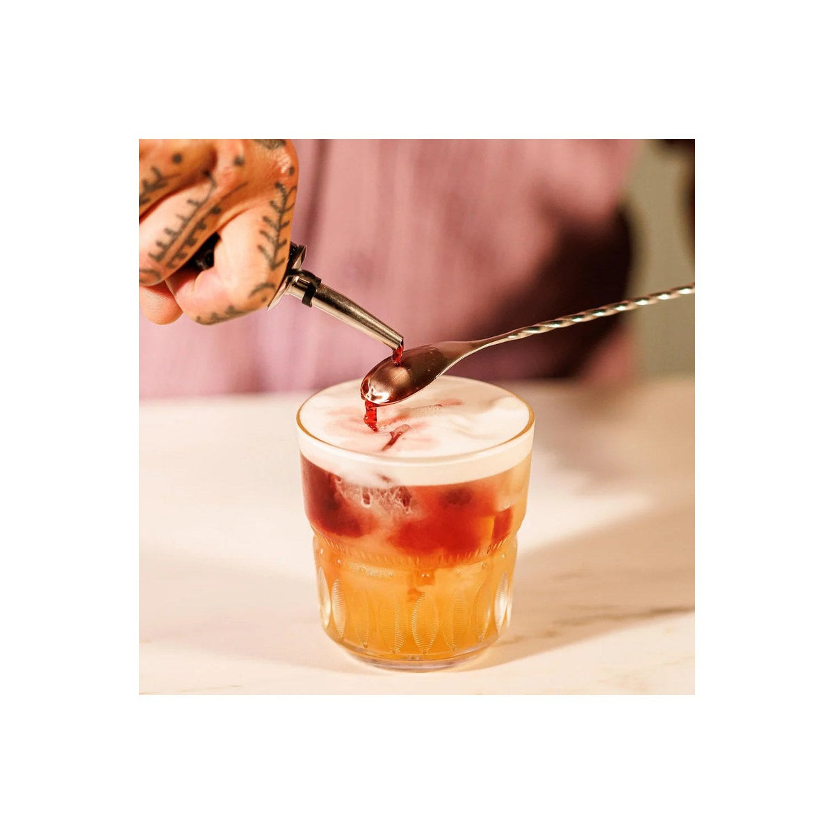 De flessenschenker in gebruik boven een cocktailglas