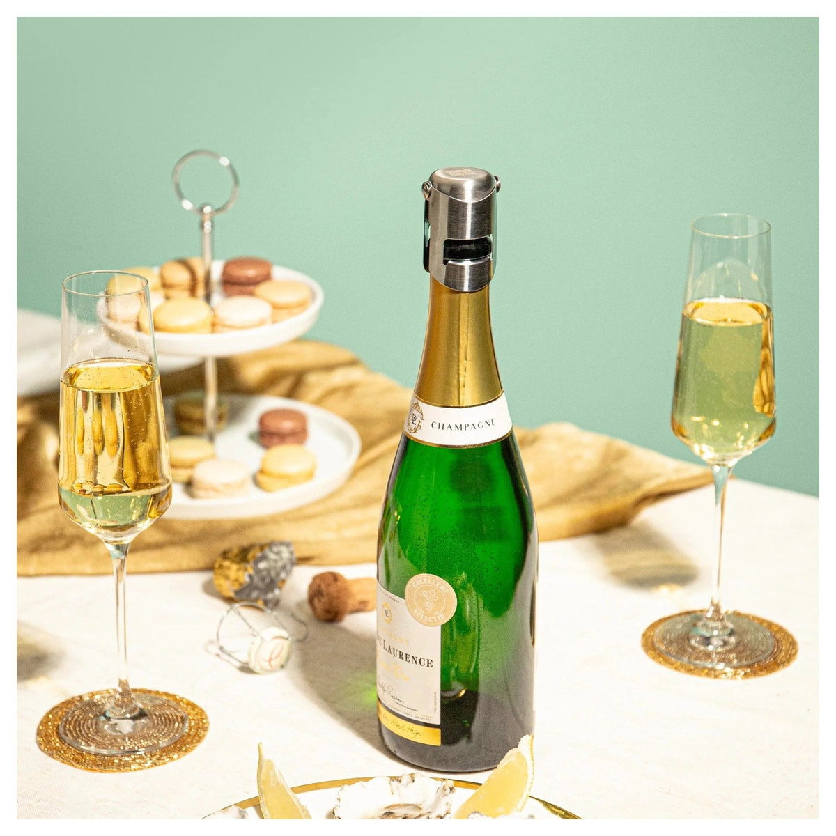 De champagnestopper op een fles champagne bij een gedekte tafel met glazen en macarons