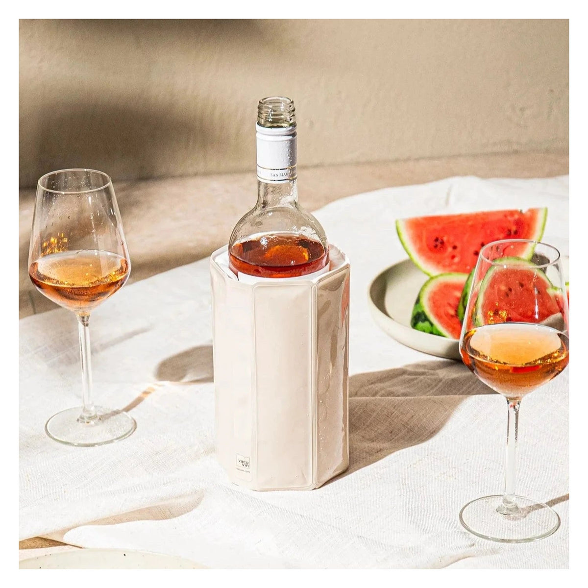 De zandkleurige koelhoes om een fles op een gedekte tafel