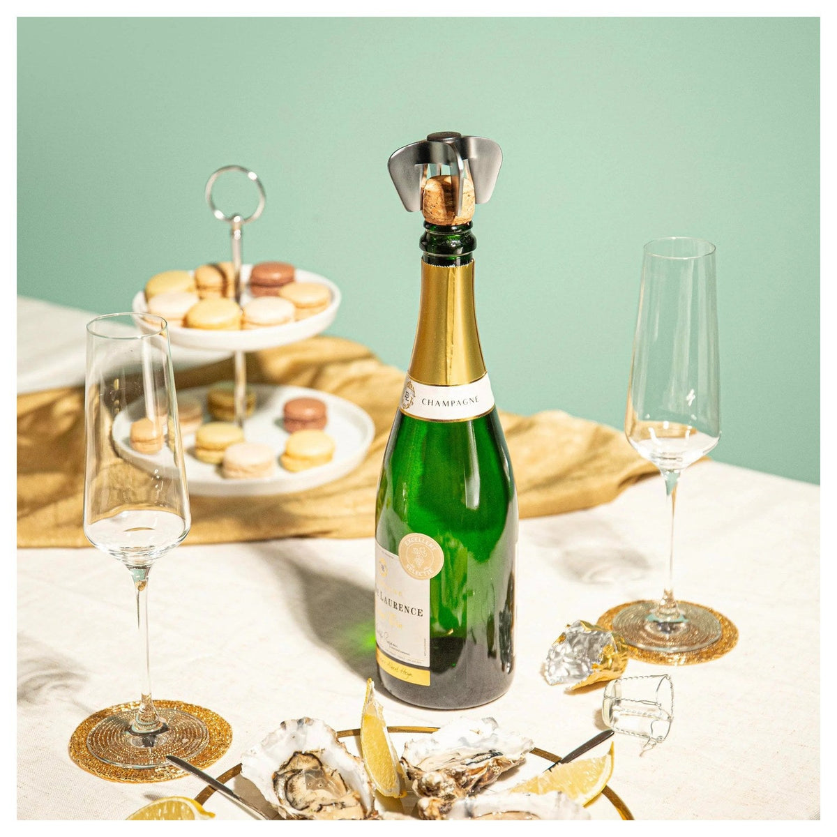 De champagne opener bij een gedekte tafel met champagne en macarons