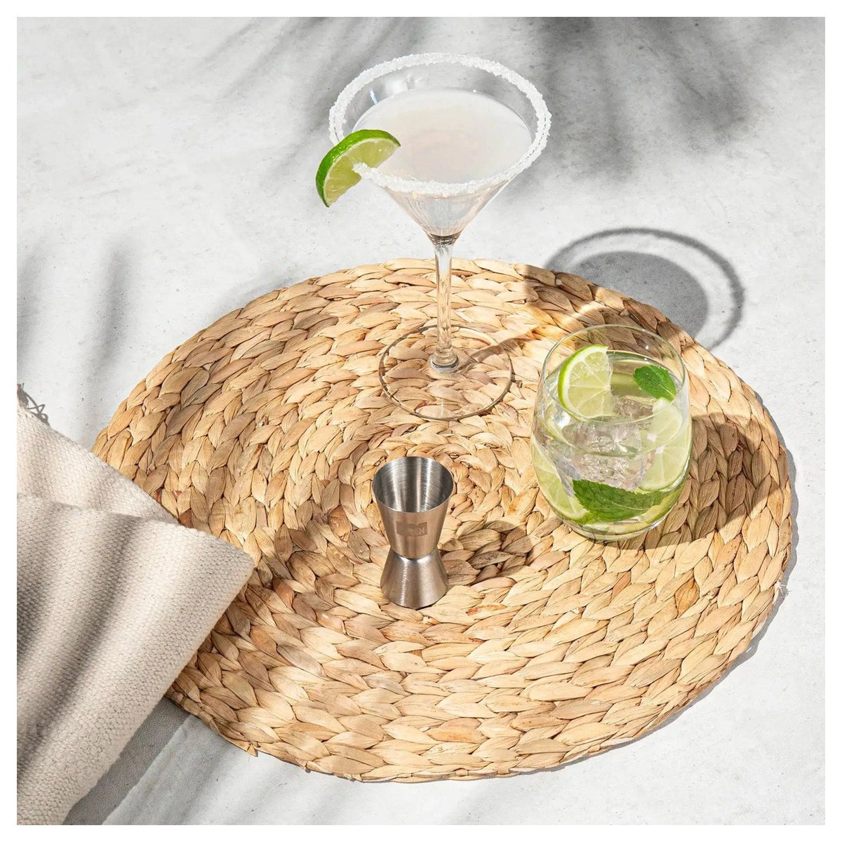 Het barmaatje naast een cocktail en een glas met limoen op een rieten onderzetter