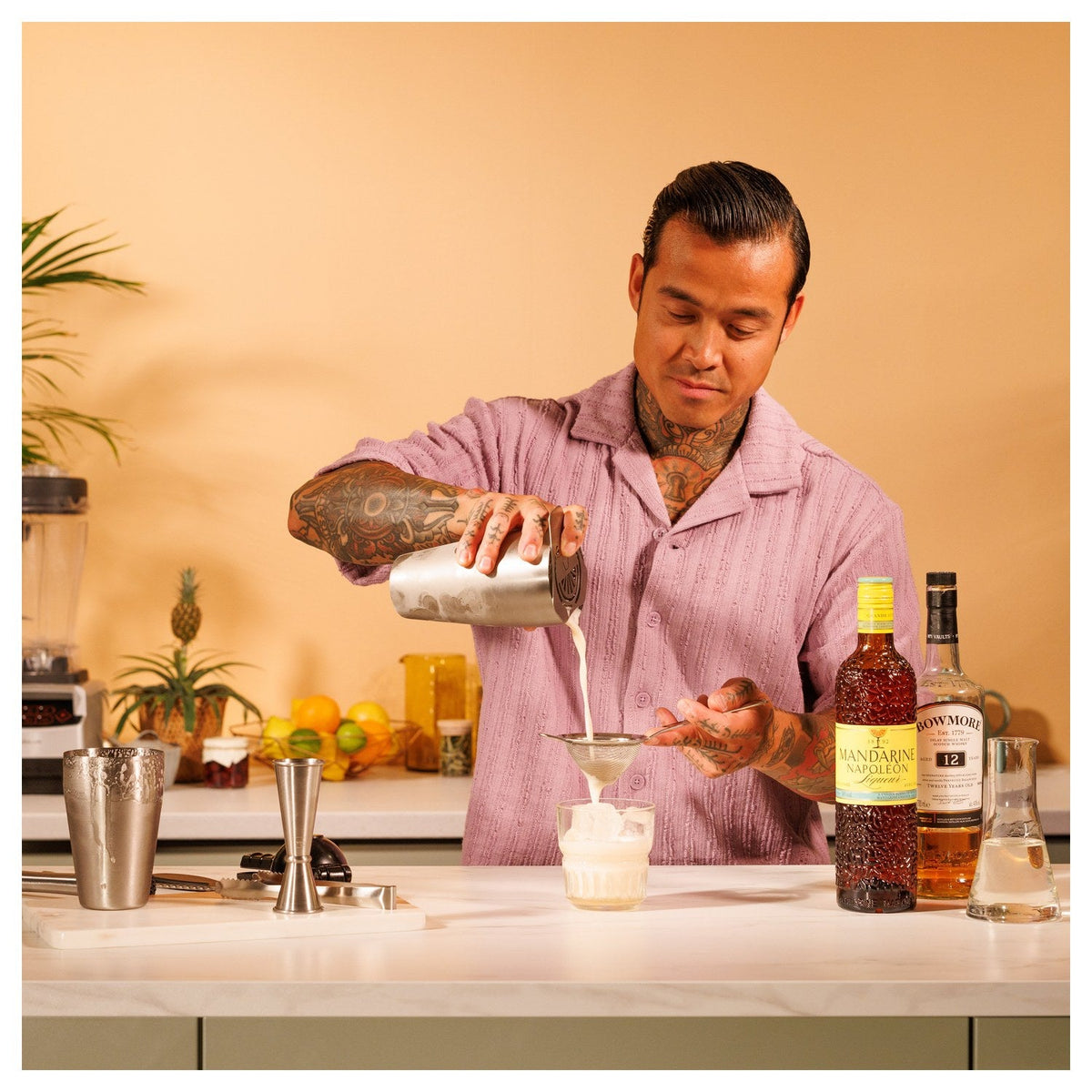 Een bartender zeeft een cocktail in een glas