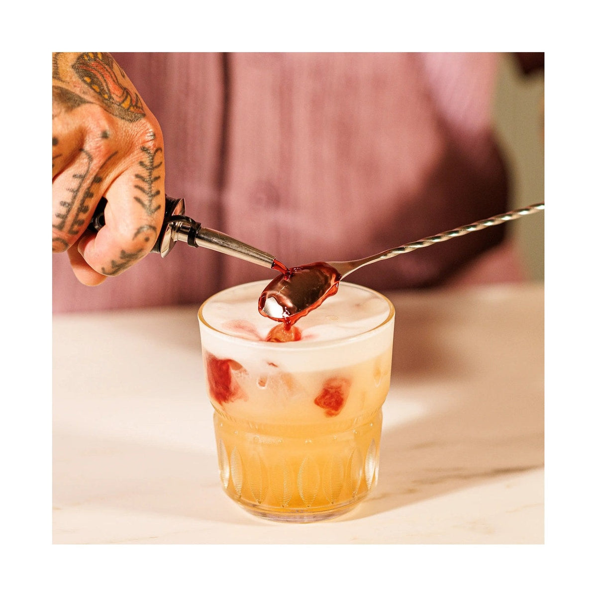 De barlepel roert een cocktail in een glas