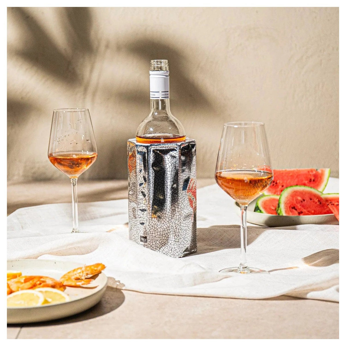 De zilveren koelhoes om een fles op een gedekte tafel met twee glazen