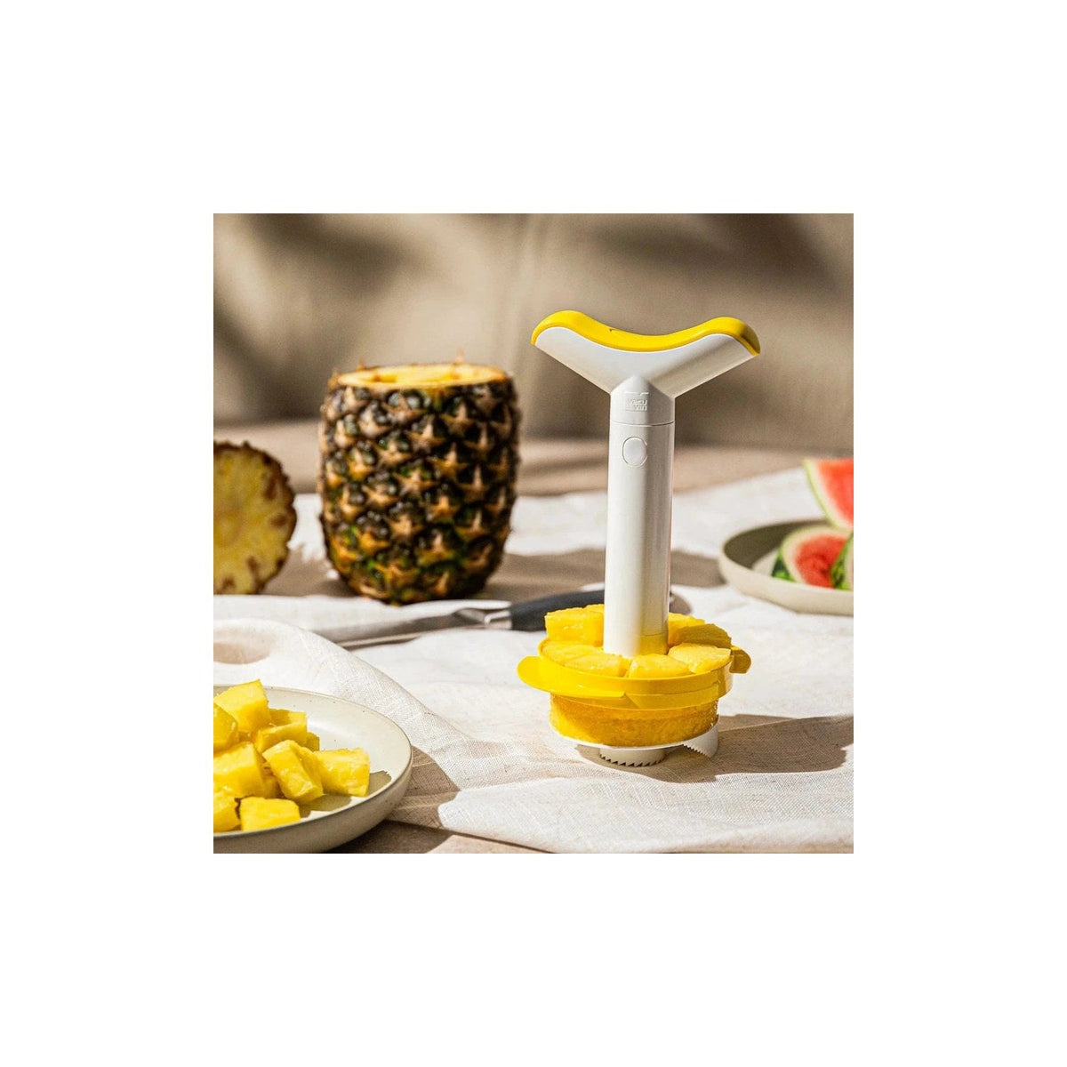 Uitgeholde ananas met een bord ananasblokjes ernaast op een gedekte tafel