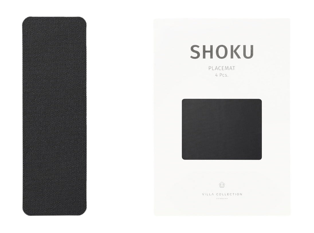 Shoku placemat Solid Black met geweven structuur naast de witte verpakking van de set van 4