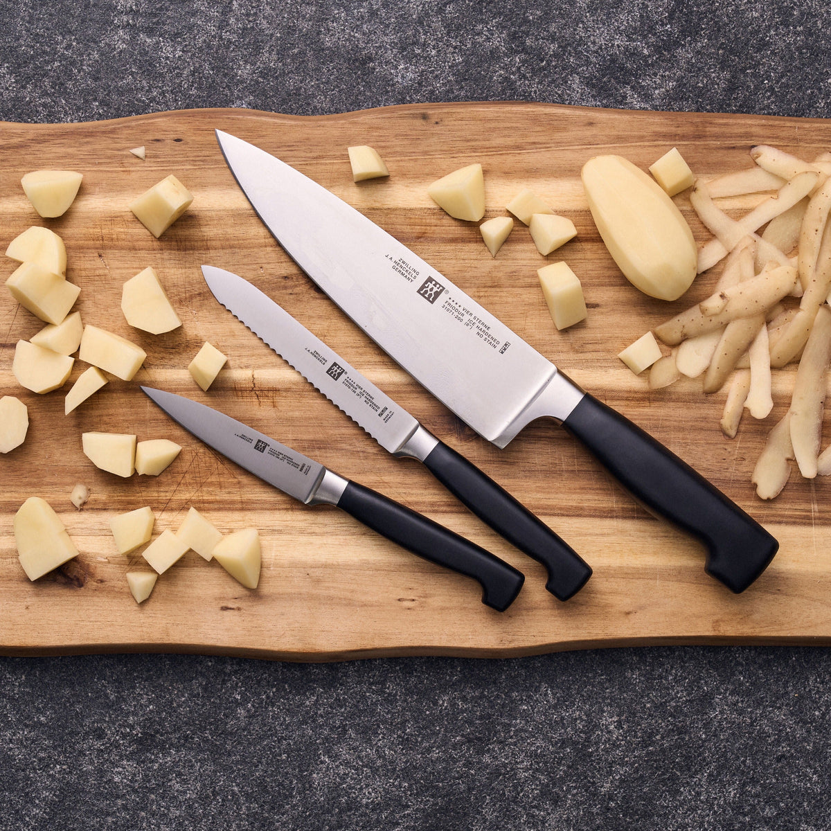 De drie messen naast elkaar op een houten plank met geschilde aardappel