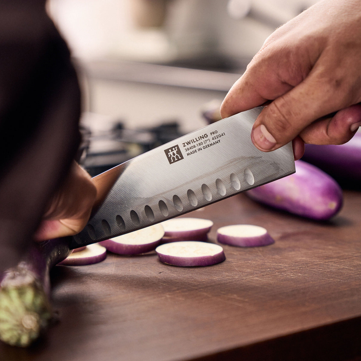 Het santokumes snijdt plakjes aubergine op een houten snijplank